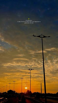 the sun is setting behind some street lamps and lights in front of a cloudy sky