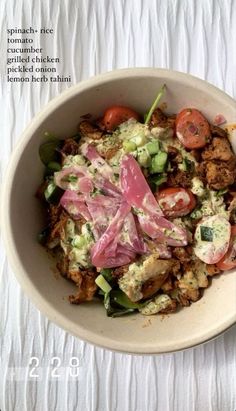 a bowl filled with meat and vegetables on top of a white table cloth next to a fork