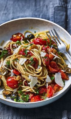 a white bowl filled with pasta, tomatoes and parmesan sprinkles