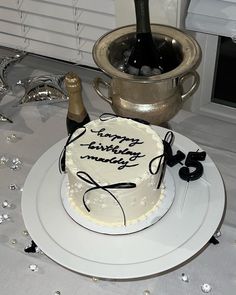 a birthday cake on a plate with a bottle of wine in the background and some glasses