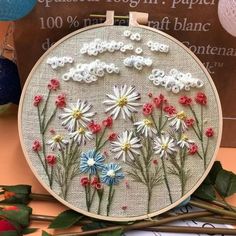 a close up of a embroidery on a table with flowers in the middle and other items around it