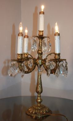 a gold candelabra with five candles on it and clear crystal beads hanging from the arms