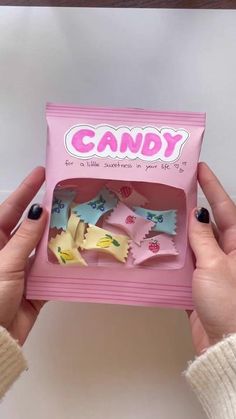 a person holding up a pink candy box