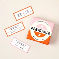 an orange and pink business card game sitting on top of a white table next to some cards