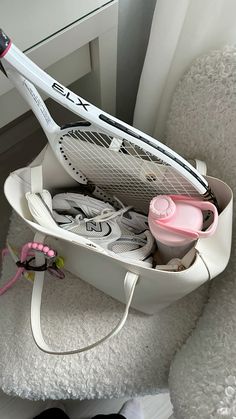 a tennis racket sitting on top of a white chair next to a pink cup