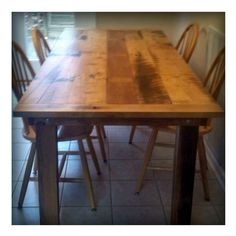 a wooden table with chairs around it in the middle of a tiled floored room