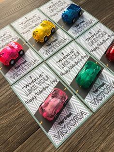 four different colored toy cars sitting on top of a wooden table next to each other