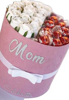 a pink hat box filled with white roses and chocolates on top of a table