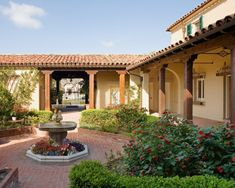 an outdoor courtyard with a fountain surrounded by greenery