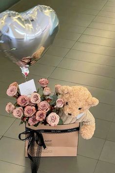 a teddy bear sitting in a box with roses and a heart shaped balloon attached to it