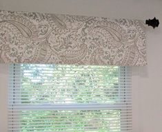 the window is decorated with white and gray paisley fabric on it's valance