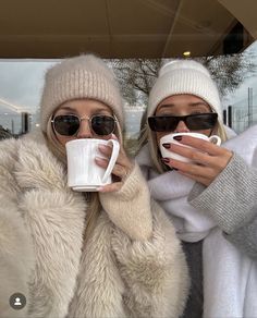 two women in winter clothing holding coffee mugs