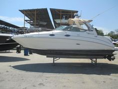 a white boat parked next to other boats in a parking lot on a sunny day