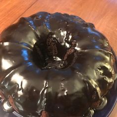 a chocolate bundt cake with frosting on a blue plate sitting on a wooden table