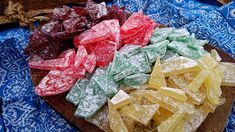 several different types of candies are on a wooden platter with blue and white cloth