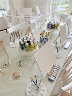 the table is set up with art supplies and watercolors in glass vases