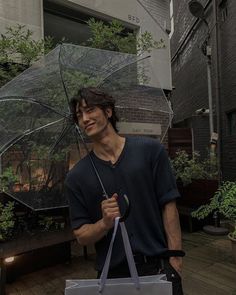 a young man holding an umbrella in front of a building on a rainy day,