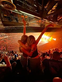 two women hugging each other in front of an arena full of people at a concert