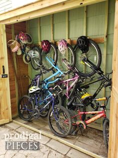 there are many bikes that are in the storage shed together and all have helmets on them