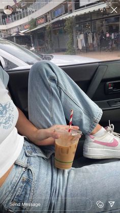 a person sitting in the back seat of a car holding a drink and a straw