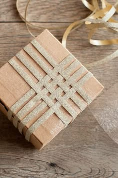 a wooden box sitting on top of a table next to a ribbon and some gold ribbons