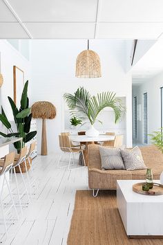 a living room filled with lots of furniture next to a dining table and potted plants