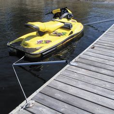 a yellow jet ski sitting on top of a body of water next to a dock