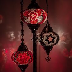 three red and white lights hanging from a black lamp post in front of a dark background