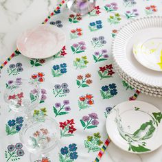 a table topped with plates and glasses on top of a tablecloth covered in flowers