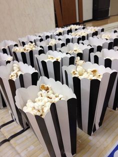 black and white striped paper bags filled with popcorn on a table in front of a wall