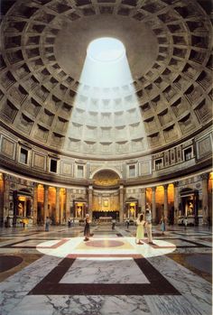 the interior of a large building with people walking around and looking up at the ceiling