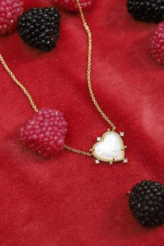 A delicate Mother of Pearl Heart Necklace with a polished heart-shaped pendant surrounded by small sparkling stones, displayed against a vibrant red backdrop interspersed with dark and light pink berries. Cz Necklace, Heart Necklace, Mother Of Pearl, Valentines Day, Unique Designs, Valentines, Gold