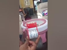 a person is holding up a red and white toothbrush in front of a pink table