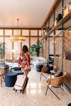 a woman is walking with her luggage through the room