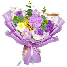 a bouquet of crocheted flowers is wrapped in purple and white paper with green leaves