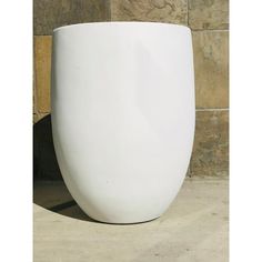 a large white vase sitting on top of a stone floor next to a brick wall