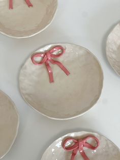 four white plates with pink bows on them