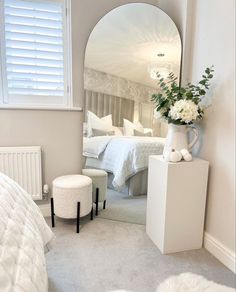 a bedroom with a large mirror and white furniture