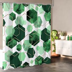 a green and white shower curtain with geometric shapes in the middle, on a bathroom floor