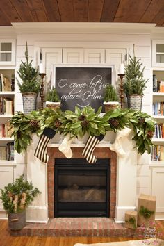 a fireplace decorated for christmas with greenery and stockings on the mantel above it