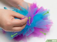 a hand holding a blue and purple tulle with an arrow pointing to the left