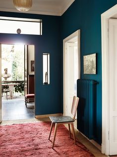 a room with blue walls and a red rug on the floor next to a radiator