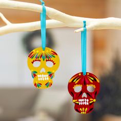 two colorful skulls hanging from a tree branch