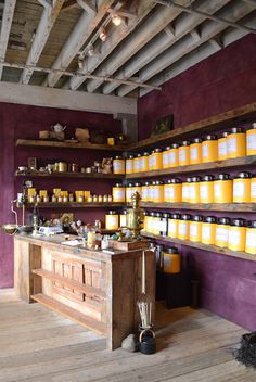 a room filled with lots of yellow jars on shelves next to a wooden counter top