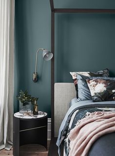 a bedroom with blue walls and a canopy bed in the corner next to a night stand