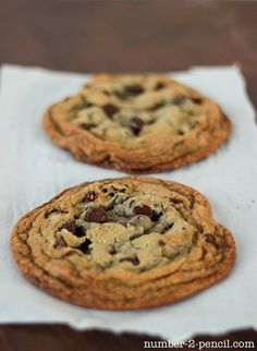 two chocolate chip cookies sitting on top of a white napkin