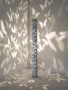 a tall vase sitting in the middle of a room next to a wall with shadows on it