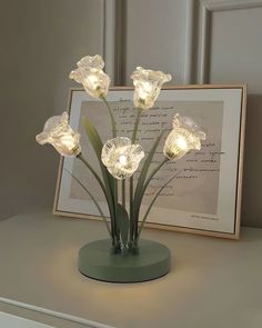 a glass vase filled with flowers sitting on top of a table next to a framed photograph