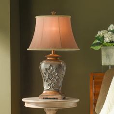 a lamp is sitting on a table next to a flower pot and chair in a room