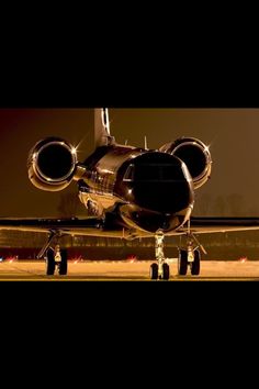 an airplane is parked on the runway at night with its lights on and it's landing gear down